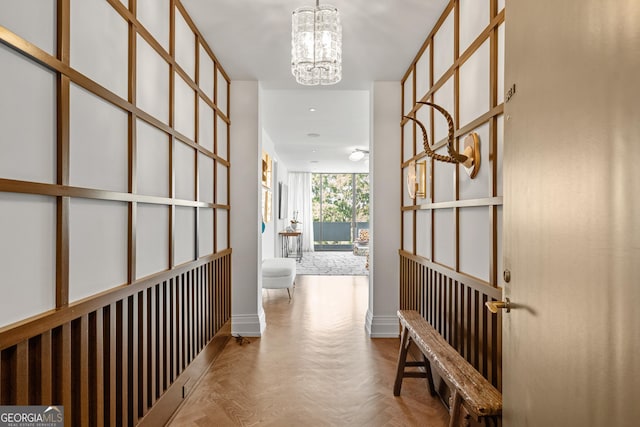 corridor with light parquet flooring and a notable chandelier