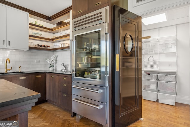 bar with dark brown cabinetry, sink, backsplash, and white cabinets