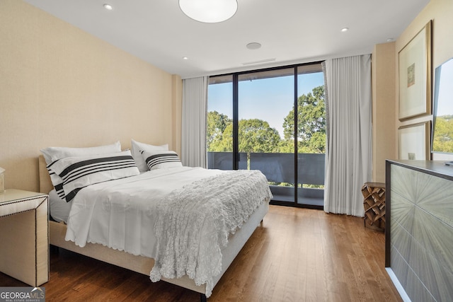 bedroom featuring a wall of windows, dark hardwood / wood-style floors, and access to outside