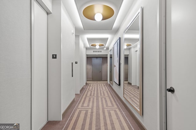 hallway with elevator and carpet