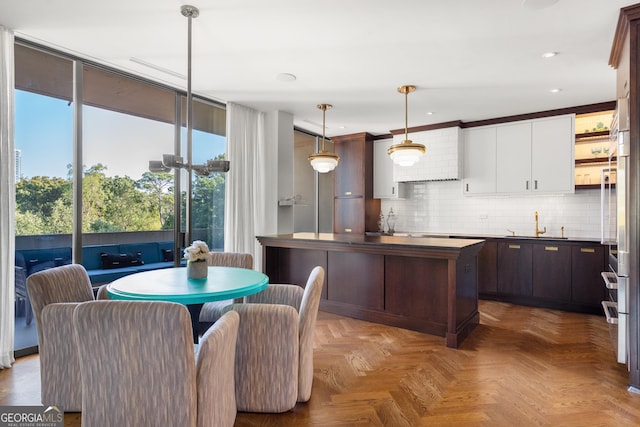 kitchen featuring backsplash, dark brown cabinets, hanging light fixtures, and white cabinets