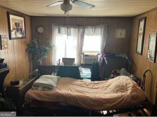 bedroom with ceiling fan and wooden walls