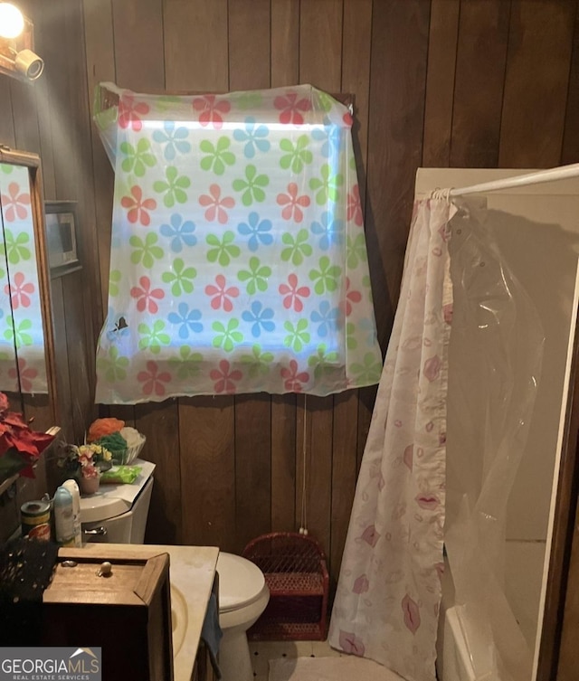 bathroom featuring vanity, toilet, and wood walls