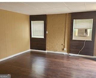 spare room featuring cooling unit, dark wood-type flooring, and a drop ceiling