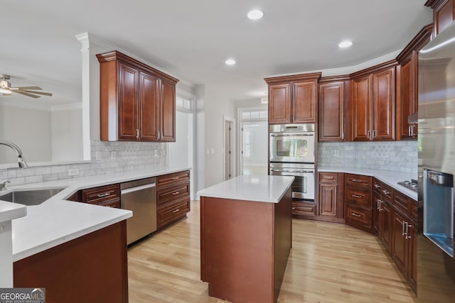 kitchen with sink, stainless steel appliances, a center island, light hardwood / wood-style floors, and kitchen peninsula