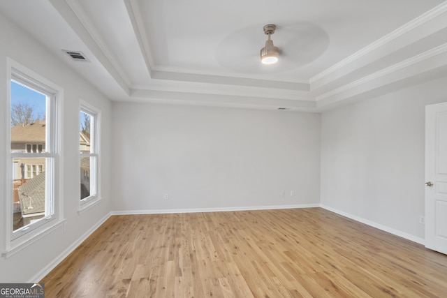 unfurnished room with ceiling fan, ornamental molding, a raised ceiling, and light wood-type flooring