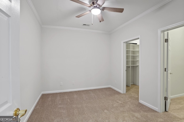 unfurnished bedroom with ornamental molding, a walk in closet, light colored carpet, and a closet