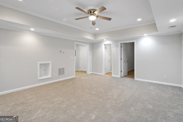 spare room featuring ornamental molding, a raised ceiling, and light carpet