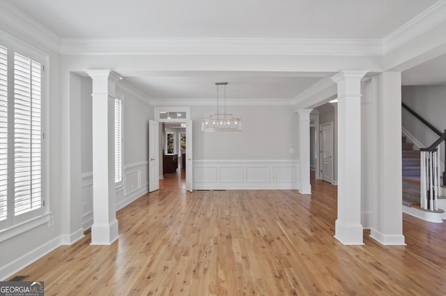 unfurnished dining area featuring crown molding, light hardwood / wood-style floors, and ornate columns