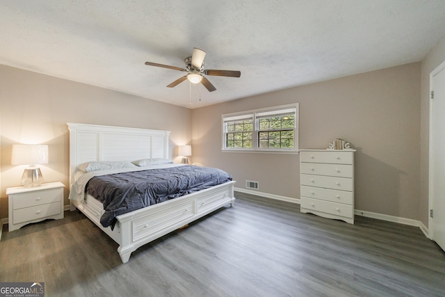 bedroom featuring ceiling fan, dark hardwood / wood-style floors, and a textured ceiling