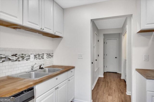 kitchen with wood counters, sink, white cabinetry, stainless steel dishwasher, and backsplash