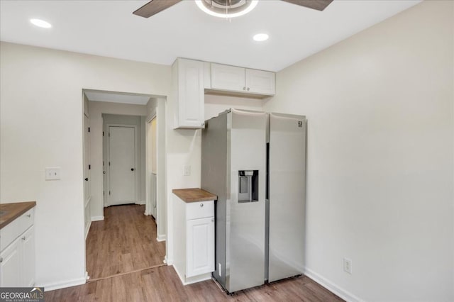 kitchen with butcher block countertops, light hardwood / wood-style flooring, stainless steel fridge, ceiling fan, and white cabinets