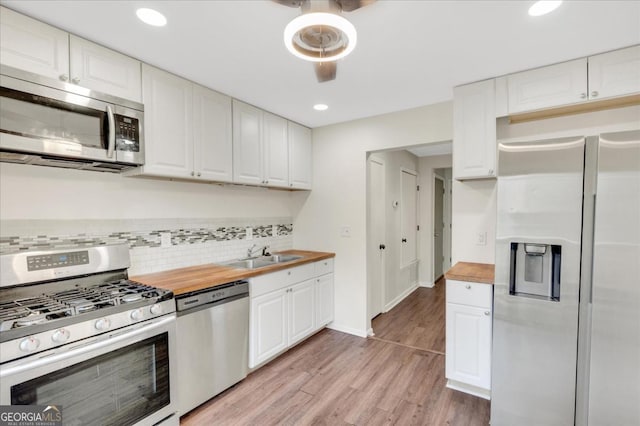 kitchen with stainless steel appliances, sink, wooden counters, and white cabinets