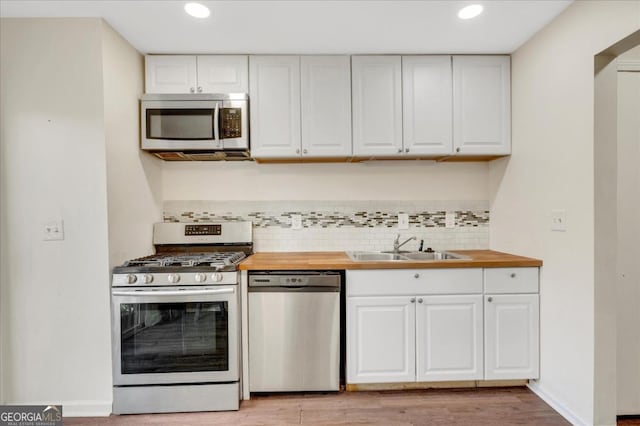 kitchen featuring butcher block countertops, white cabinets, and appliances with stainless steel finishes