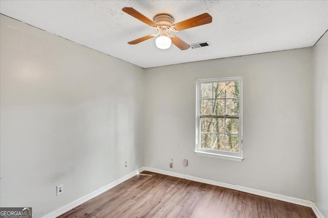 empty room with hardwood / wood-style flooring, a textured ceiling, and ceiling fan