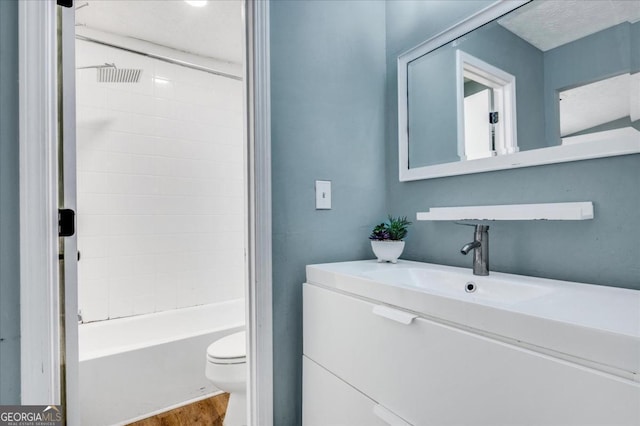 full bathroom featuring vanity, tiled shower / bath, hardwood / wood-style flooring, and toilet