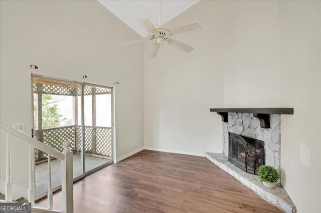 unfurnished living room featuring ceiling fan, wood-type flooring, a stone fireplace, and high vaulted ceiling