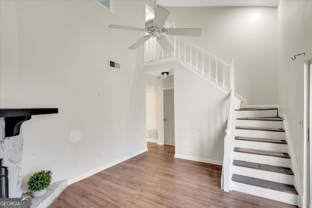 staircase featuring hardwood / wood-style floors, ceiling fan, and a high ceiling