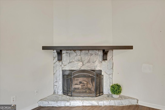 interior details featuring hardwood / wood-style flooring and a stone fireplace