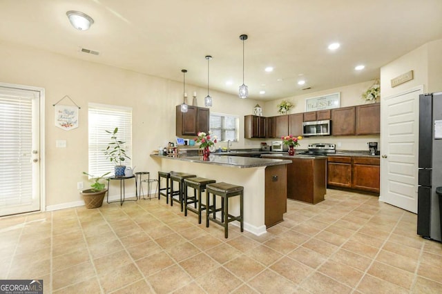 kitchen featuring sink, appliances with stainless steel finishes, hanging light fixtures, a kitchen breakfast bar, and kitchen peninsula