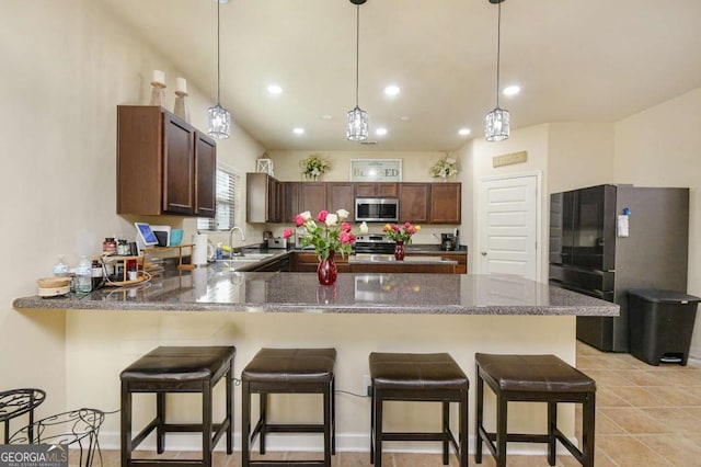 kitchen featuring sink, a kitchen breakfast bar, kitchen peninsula, pendant lighting, and stainless steel appliances