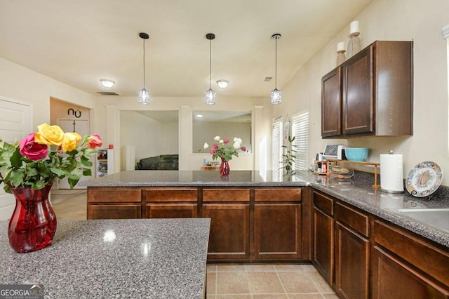 kitchen featuring pendant lighting, light tile patterned flooring, and dark brown cabinets