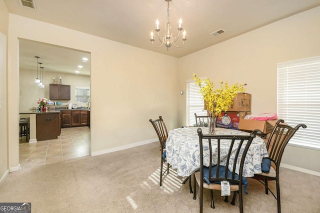 dining area with a healthy amount of sunlight, light colored carpet, and a notable chandelier