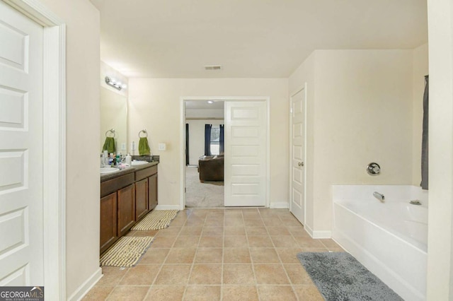 bathroom with a washtub, vanity, and tile patterned floors