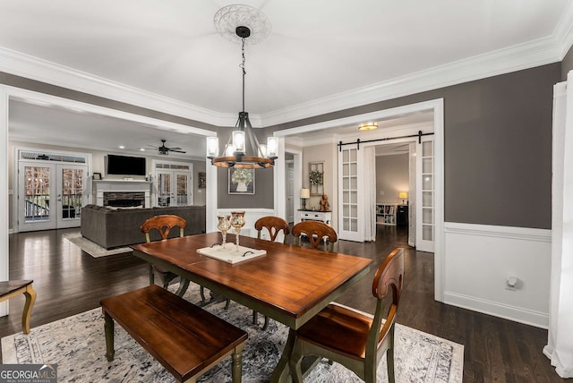 dining room featuring ornamental molding, a barn door, and dark hardwood / wood-style flooring