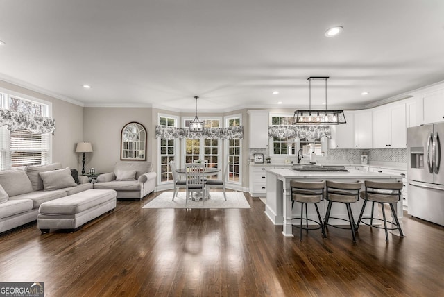 living room featuring an inviting chandelier, dark wood-type flooring, and ornamental molding