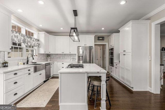 kitchen featuring pendant lighting, sink, appliances with stainless steel finishes, white cabinetry, and a kitchen island