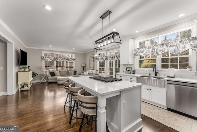 kitchen with pendant lighting, white cabinetry, sink, a center island, and stainless steel appliances