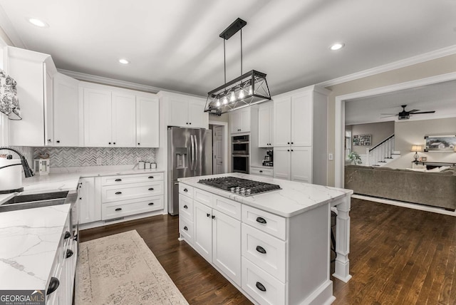 kitchen featuring white cabinetry, decorative light fixtures, appliances with stainless steel finishes, and a kitchen island