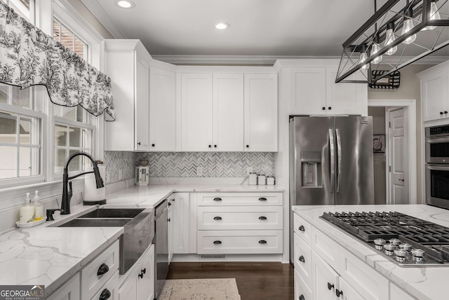 kitchen with light stone counters, pendant lighting, stainless steel appliances, and white cabinets