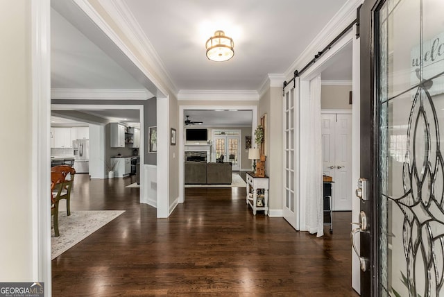 entrance foyer featuring dark wood-type flooring, ornamental molding, and a barn door