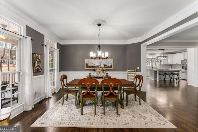 dining area with crown molding, dark hardwood / wood-style floors, sink, and a notable chandelier