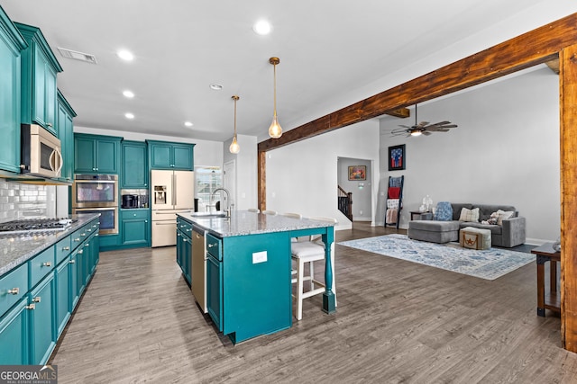 kitchen featuring blue cabinets, appliances with stainless steel finishes, a kitchen breakfast bar, pendant lighting, and a kitchen island with sink