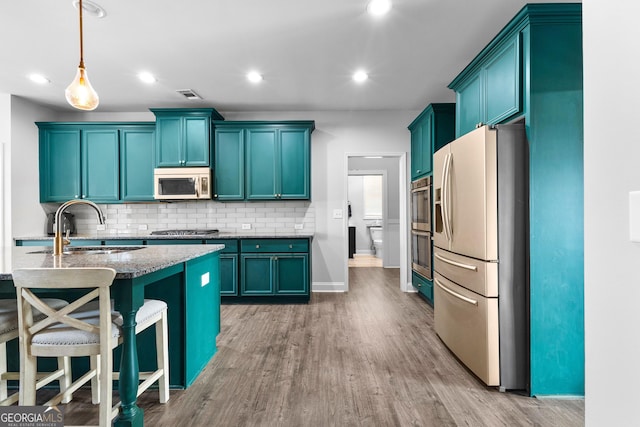 kitchen featuring sink, hardwood / wood-style flooring, pendant lighting, stainless steel appliances, and decorative backsplash