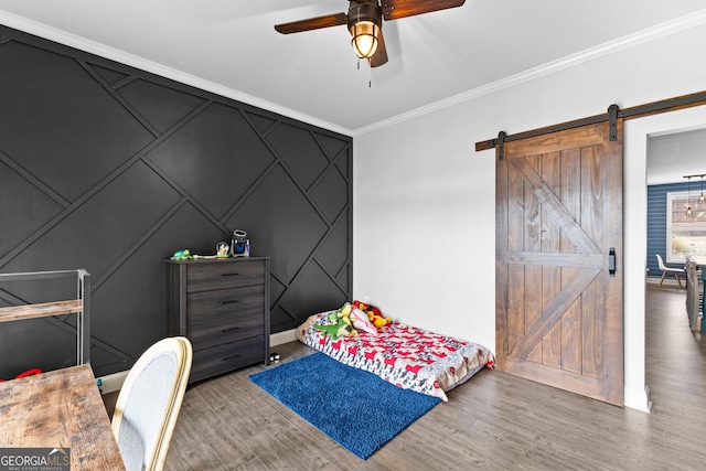 bedroom with hardwood / wood-style floors, crown molding, a barn door, and ceiling fan