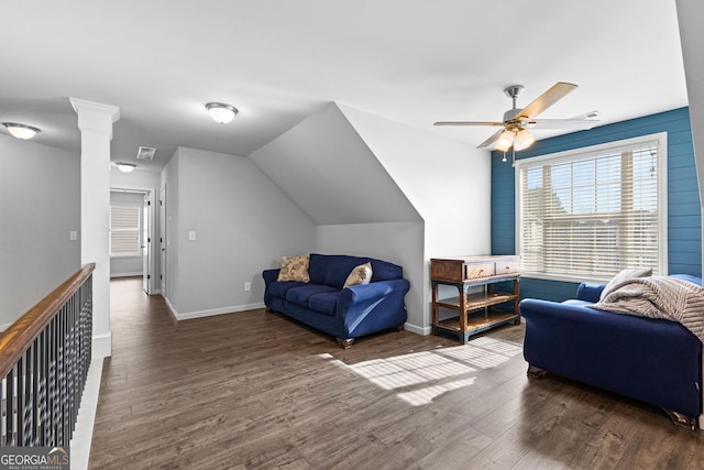 interior space featuring dark wood-type flooring, ceiling fan, vaulted ceiling, and decorative columns