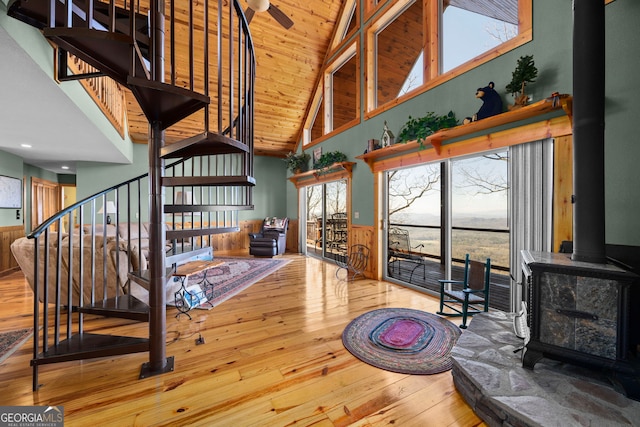 interior space with high vaulted ceiling, wood-type flooring, a wood stove, ceiling fan, and wood ceiling