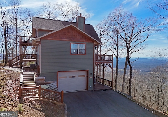 view of side of property with a garage, a balcony, and a mountain view