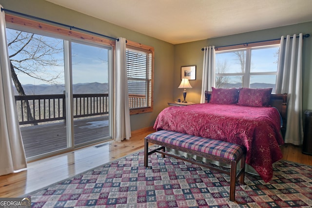 bedroom featuring a mountain view, hardwood / wood-style floors, and access to exterior