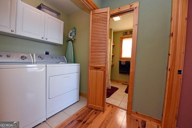 clothes washing area with cabinets, washer and dryer, and light wood-type flooring