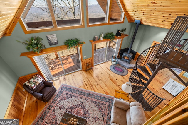 living room featuring hardwood / wood-style flooring, lofted ceiling, a wood stove, and wooden ceiling