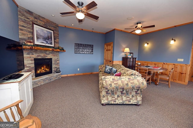 carpeted living room featuring ornamental molding, ceiling fan, and a fireplace