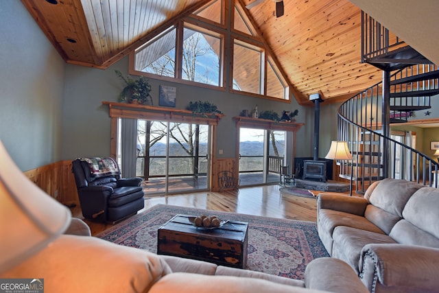 living room featuring wood ceiling, wood-type flooring, high vaulted ceiling, and a wood stove