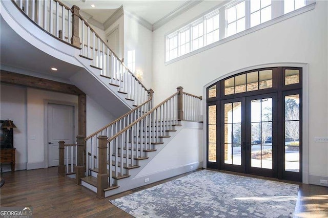 entrance foyer with a high ceiling, crown molding, dark hardwood / wood-style flooring, and french doors