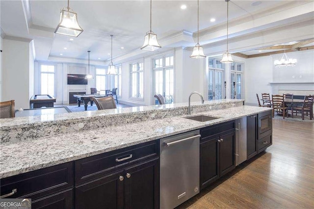 kitchen featuring a tray ceiling, decorative light fixtures, dishwasher, and sink