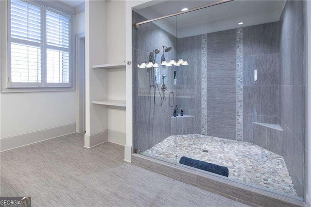 bathroom featuring built in shelves and a shower with shower door